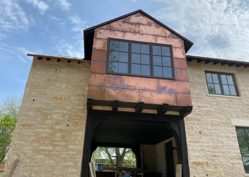 Copper metal panel facade on a stone building for Roof Repair in Blackwell