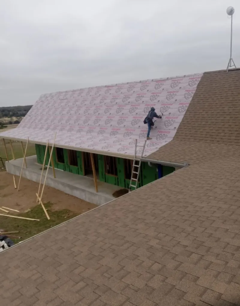 Worker preparing underlayment for a metal roof installation in Blackwell